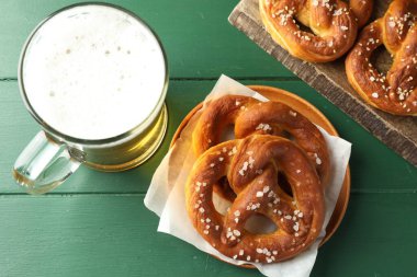 Lezzetli krakerler ve yeşil ahşap masada bir bardak bira.