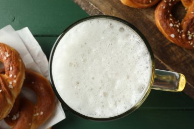 Lezzetli krakerler ve yeşil ahşap masada bir bardak bira.