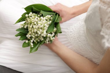 Gelin, vadideki güzel zambaklardan bir buket, kapalı bir kanepede, yakın plan.