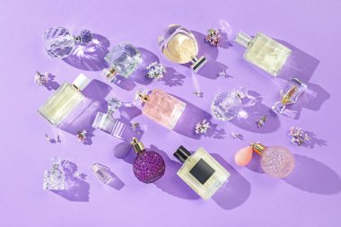 Düz kompozisyon, parfüm şişeleri ve mor arka planda leylak çiçekleri vardı.