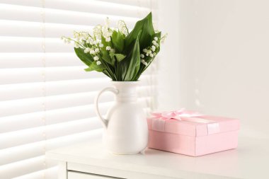 Vadi çiçeklerinin güzel zambakları ve kapalı alanda beyaz bir masada hediye.