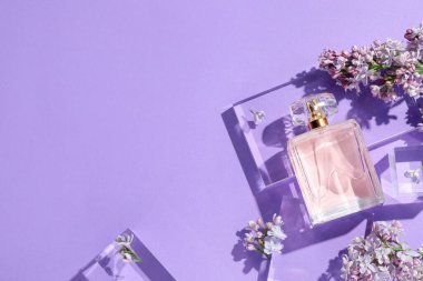 Düz kompozisyon, mor arka planda parfüm şişesi ve leylak çiçekleri vardı. Metin için boşluk