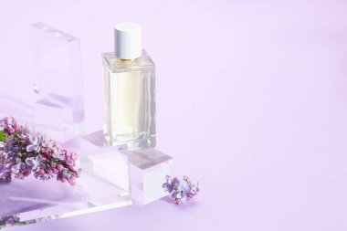 Mor arka planda parfüm şişesi ve leylak çiçeklerinin şık sunumu, yakın plan. Metin için boşluk