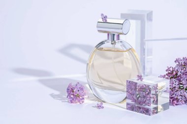 Açık gri arka planda parfüm şişesi ve leylak çiçeklerinin şık sunumu, yakın plan. Metin için boşluk
