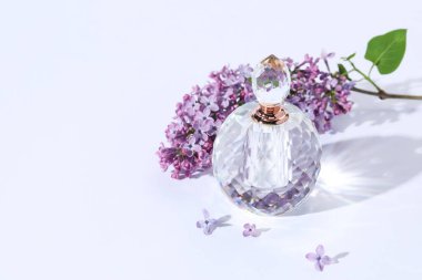 Parfüm şişesi ve açık gri arka planda leylak çiçekli dal. Metin için boşluk
