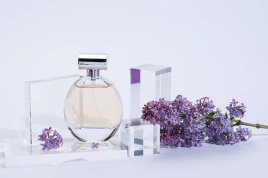 Açık gri arka planda parfüm şişesi ve leylak çiçeklerinin şık sunumu, yakın plan