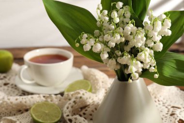 Vadinin güzel zambakları vazoda çiçek, ahşap masada çay ve limon, yakın plan.