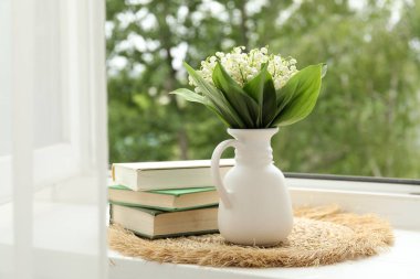 Vazodaki nilüfer çiçekleri ve içerideki pencere kenarındaki kitaplar.