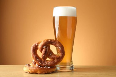 Lezzetli krakerler ve ahşap masada bir bardak bira bej renkli arka plan, yakın plan.