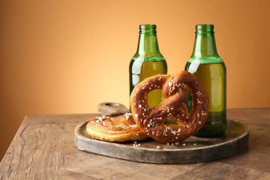 Lezzetli krakerler ve bira şişeleri ahşap masa üzerinde bej renkli gradyan arka plan, yakın çekim