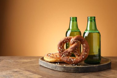 Lezzetli krakerler ve bira şişeleri ahşap masada, bej renkli arka planda, yakın plan. Metin için boşluk