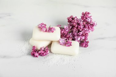 Beyaz mermer masada sabun, deniz tuzu ve leylak çiçekleri.