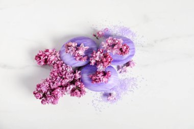 Sabun çubukları, deniz tuzu ve leylak çiçekleri beyaz mermer masada, düz yatıyordu.