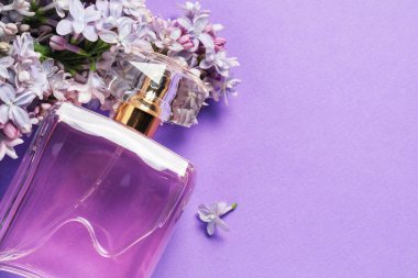 Üzerinde parfüm ve mor arka planda leylak çiçekleri olan bir şişe. Metin için boşluk