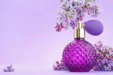 Parfüm şişesi ve mor arkaplanda leylak çiçekleri, yakın plan. Metin için boşluk
