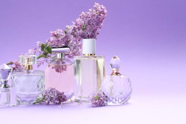 Parfümlü şişeler ve mor arkaplanda leylak çiçekleri, yakın plan. Metin için boşluk