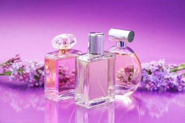 Parfümlü şişeler ve ayna yüzeyinde leylak çiçekleri renk değişimine karşı, yakın plan