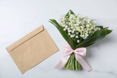 Vadideki güzel zambak çiçekleri ve beyaz mermer arka planda bir zarf.