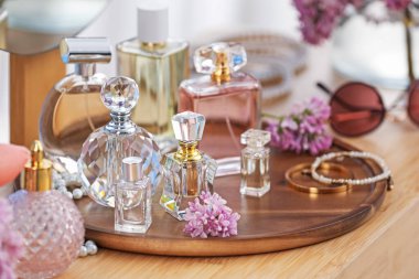 Parfümlü şişeler, leylak çiçekleri ve ahşap masa üzerindeki aksesuarlar, yakın plan.