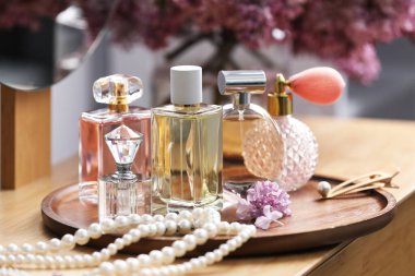 Parfüm şişeleri, aksesuarlar ve ahşap masada leylak çiçekleri, yakın plan.