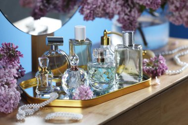 Parfümlü şişeler, eflatun çiçekleri ve tuvalet masasında aksesuarlar.