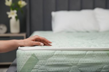 Yatakta yumuşak yatağa dokunan bir kadın, yakın plan. Metin için boşluk