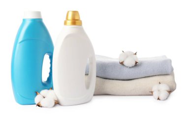 Yumuşatıcı şişeler, üst üste yığılmış giysiler ve beyaz üzerine izole edilmiş pamuk çiçekleri.