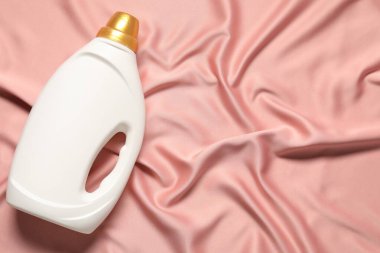 Bir şişe yumuşatıcı ve pembe kumaş, üst manzara. Metin için boşluk