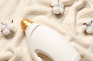 Bir şişe yumuşatıcı ve pamuk çiçekleri yumuşak bez üzerinde, düz yatıyordu.
