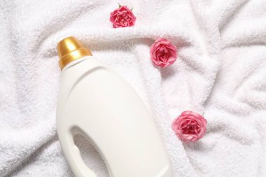 Bir şişe yumuşatıcı ve terli havluda çiçekler, düz uzanmış.