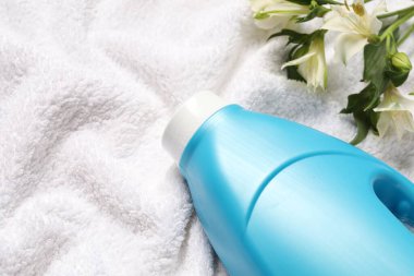 Bir şişe yumuşatıcı ve Terry Havlu 'nun üstünde çiçekler. Metin için boşluk