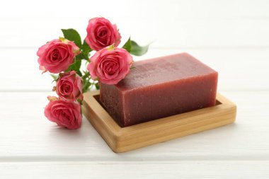 Sabun barı ve beyaz ahşap masada güzel güller, yakın plan.