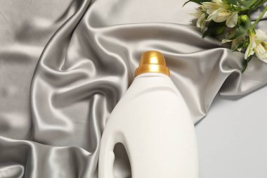 Açık gri arkaplanda kumaş yumuşatıcı, çiçekler ve renkli kumaş.