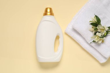 Bir şişe yumuşatıcı, çiçekler ve bej arka planda terry havlular.