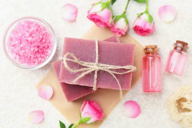 Sabun çubukları, deniz tuzu, temel yağlar ve bej masadaki güzel güller, düz uzanma.