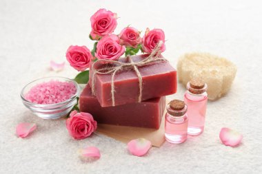 Sabun çubukları, deniz tuzu, temel yağlar ve bej masadaki güzel güller, yakın plan.