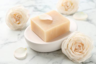 Sabun çubuğu ve çiçekler beyaz mermer masada, yakın plan.