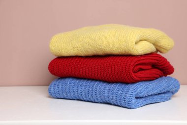 Beyaz masadaki yün süveter yığını renk arkaplanı, yakın plan