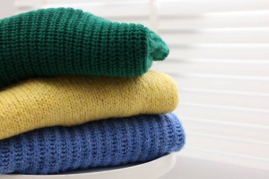 Pencerenin yanındaki masada yün süveter yığını, yakın plan.