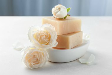 Aromatik sabun çubukları ve güller ışık masasında.