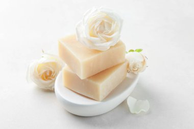 Aromatik sabun çubukları ve güller ışık masasında.