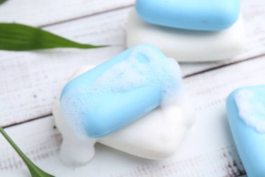 Köpüklü sabun çubukları beyaz ahşap masa, yakın plan.