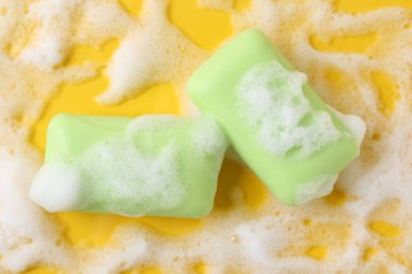 Sarı arka planda köpüklü sabun çubukları, düz yatış