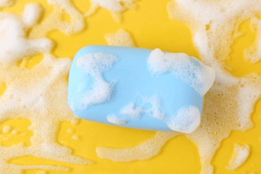 Sarı zemin üzerinde köpük olan sabun çubuğu, üst görünüm