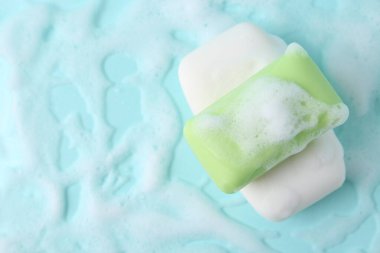 Açık mavi arka planda köpüklü sabun çubukları, üst manzara. Metin için boşluk