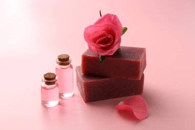 Sabun barları, kozmetik ürünleri ve pembe arka planda güzel bir gül.
