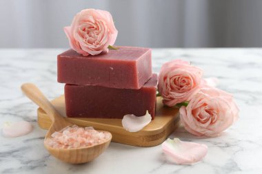 Sabun çubukları, deniz tuzu ve beyaz mermer masada güzel güller, yakın plan.