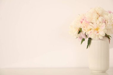 Beyaz duvarın yanındaki masada bir buket güzel şakayık. Metin için boşluk