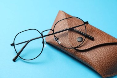 Açık mavi arka planda şık gözlüklü çanta, yakın plan