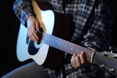 Siyah arka planda gitar çalan kadın, yakın plan